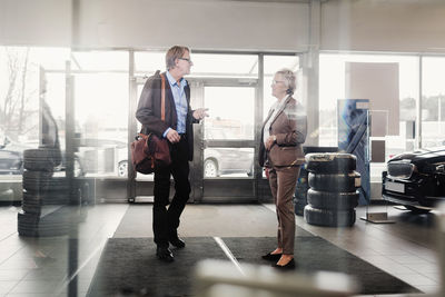 Senior man talking to saleswoman in car dealership