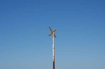 Low angle view of railroad crossing sign against clear blue sky