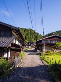 Walkway amidst houses and trees against sky