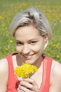 Portrait of smiling woman holding yellow flower
