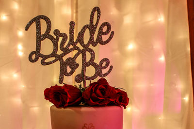 Close-up of text and roses against illuminated lights