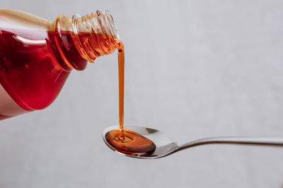 Covid -liquid medicine bottle being poured out onto a metal spoon