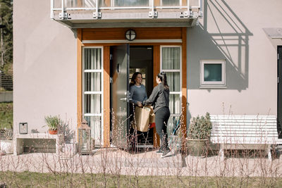 Female customer receiving package from delivery woman