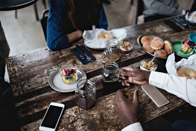 High angle view of man holding drink jar while sitting with friends at dining table in restaurant