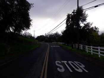 Road by trees against sky