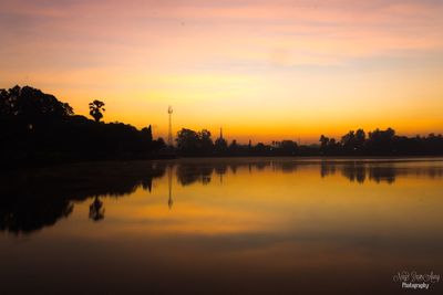 Reflection of trees in water at sunset