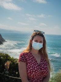 Portrait of teenage girl at beach against sky