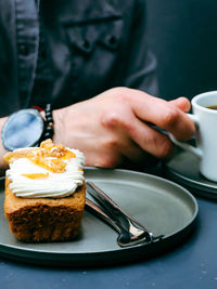 Midsection of man having cake on table