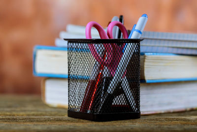 Close-up of pens and scissor in desk organizer on table at home
