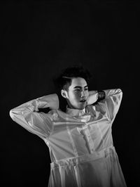 Portrait of young man looking away against black background