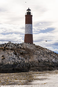 Lighthouse by sea against sky