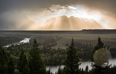 Scenic view of mountains against glowing sky while raining