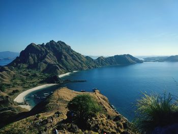 Scenic view of sea and mountains against clear blue sky