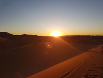 Scenic view of desert against clear sky during sunset