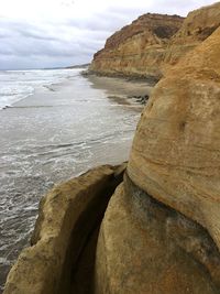 Rock formation at beach against sky