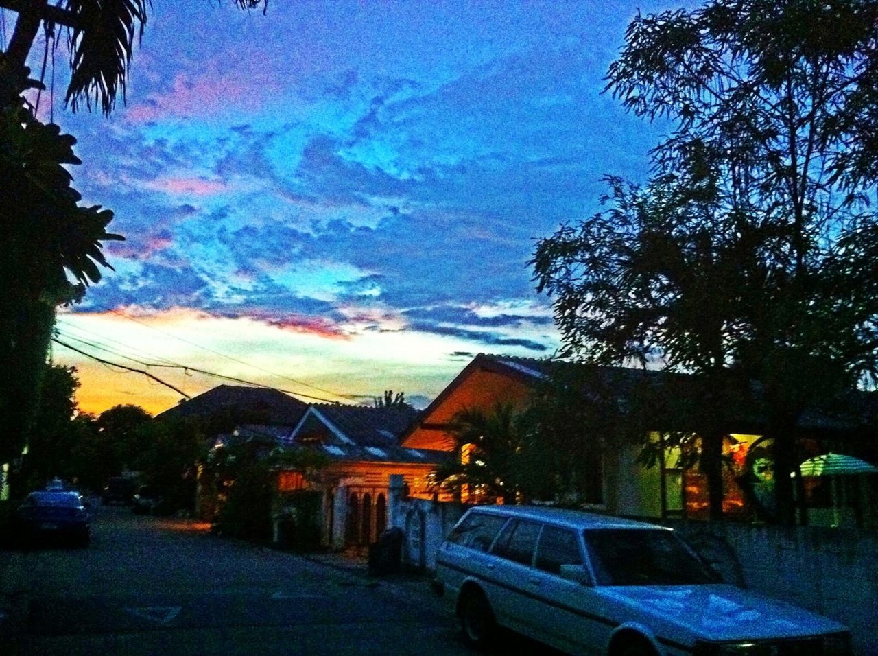 sky, tree, building exterior, architecture, built structure, sunset, cloud - sky, street, dusk, car, transportation, house, road, land vehicle, illuminated, cloud, outdoors, mode of transport, no people, cloudy