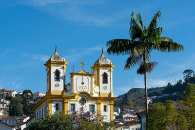 Low angle view of palm trees and church against sky