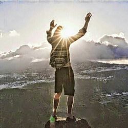 Rear view of woman standing on mountain against sky