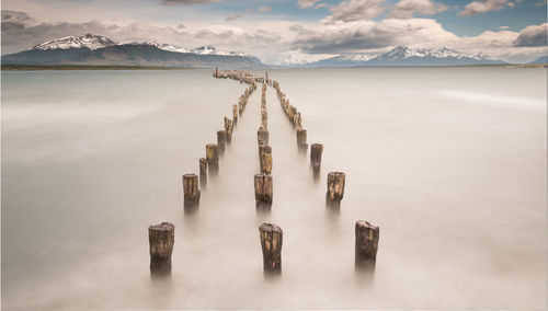 Panoramic view of wooden post by lake against sky