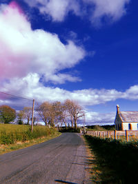 Road amidst field against sky