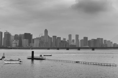 City skyline by calm river against sky