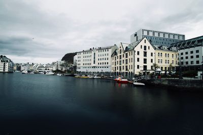 Buildings by river against sky in city