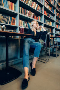 Full length of woman sitting on book