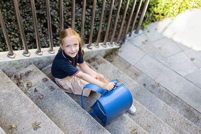 Portrait of young woman standing on footpath