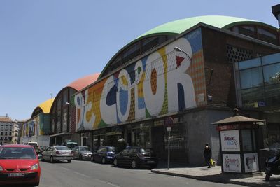 Cars parked in front of city street against clear sky