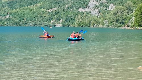 People sitting on river against sky