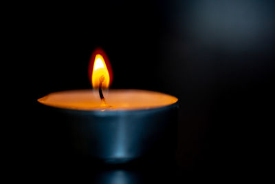 Close-up of burning candle against black background