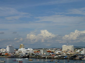 Sailboats moored in harbor by buildings against sky