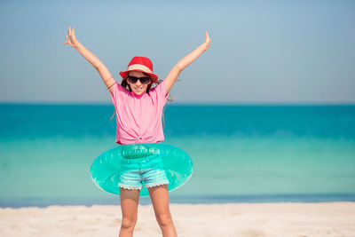 Low section of person with arms raised on beach against sky
