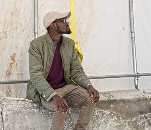 Young man sitting on wall