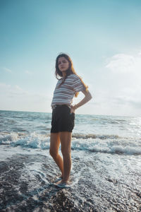 Full length portrait of young woman standing on beach