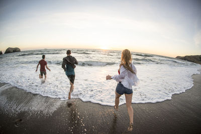 Group of teenagers having fun on beach at sunset