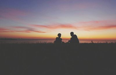 Silhouette women on beach against romantic sky at sunset