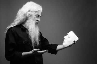 Man holding while looking at mask against gray background