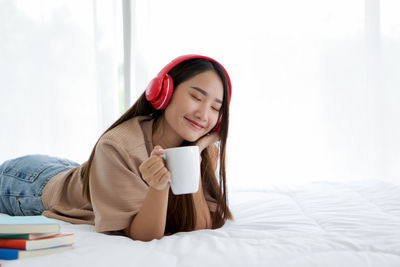 Young woman drinking coffee cup on bed