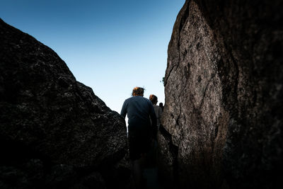 Rear view of man and woman standing by rock