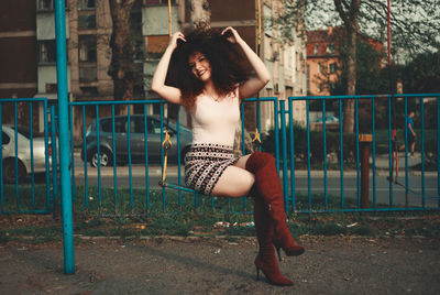 Portrait of young woman with arms raised in park