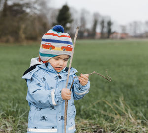 Girl holding stick while standing on land