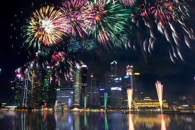 Firework display over illuminated buildings in city at night