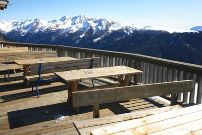 Wooden table and snowcapped mountains against sky