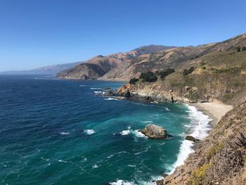 Scenic view of sea and mountains against clear blue sky