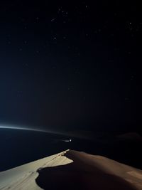 Cropped image of airplane wing against sky at night