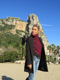Portrait of beautiful young woman standing on land against sky