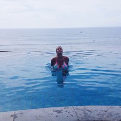 Woman swimming in infinity pool against sea