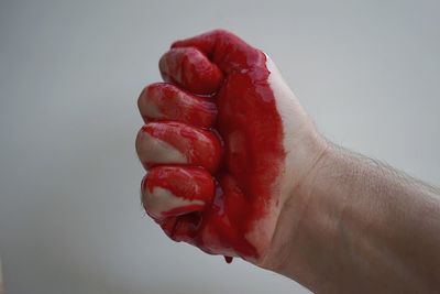 Cropped image of red hand against gray background