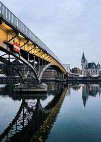 Bridge over river in city against sky